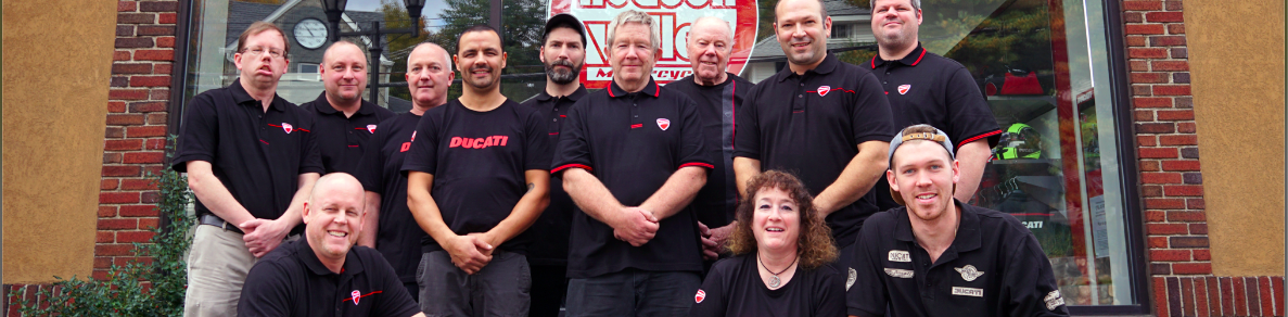 two guys riding a red bike on a roadway at full speed on kindof clear gray sky